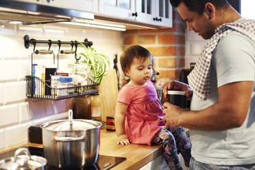 Father and baby girl cooking together in kitchen at home - ABIF01103