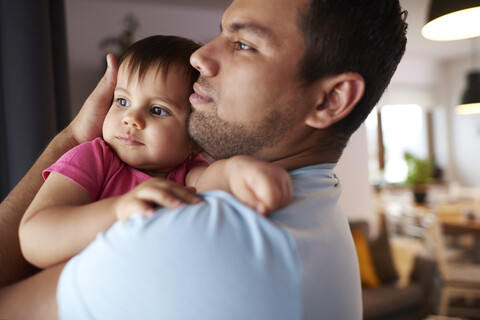 Liebevoller Vater, der seine kleine Tochter zu Hause umarmt, lizenzfreies Stockfoto