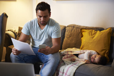 Multitasking-Vater, der zu Hause arbeitet, während sein kleines Mädchen auf dem Sofa schläft - ABIF01111