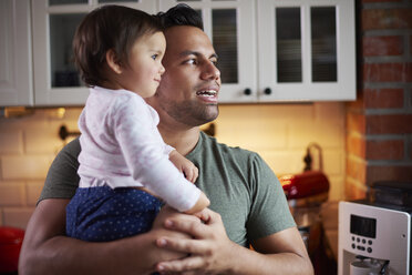 Father holding baby girl in kitchen at home - ABIF01113