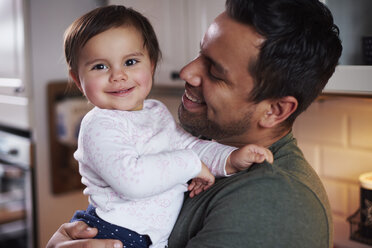 Portrait of smiling father holding baby girl at home - ABIF01116