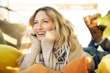 Portrait of smiling blond mature woman relaxing in winter garden - DMOF00092