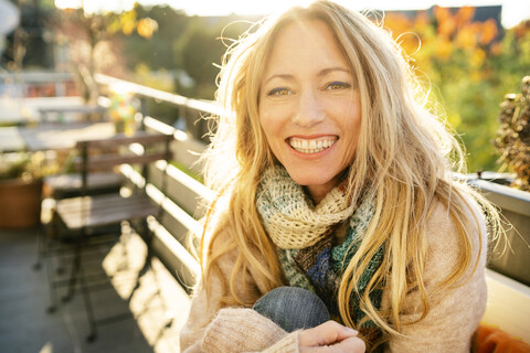 Portrait of happy blond mature woman on balcony in autumn stock photo