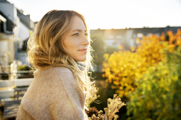 Blonde reife Frau genießt sonnigen Herbsttag auf dem Balkon - DMOF00100