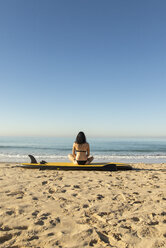 Spanien, Andalusien, Tarifa, Frau sitzt auf Stand Up Paddle Board am Strand - KBF00392