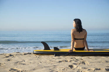 Spanien, Andalusien, Tarifa, Frau sitzt auf Stand Up Paddle Board am Strand - KBF00393