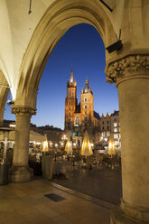 Poland, Krakow, city by night, view to St. Mary's Church from the arcade of the Coth Hall in Old Town - ABOF00407