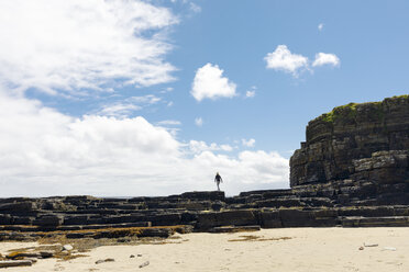 Frau, die am Strand in Schottland auf Felsen spazieren geht - FOLF09638