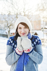 Junge Frau mit Tasse im Schnee in Enskede, Schweden - FOLF09661