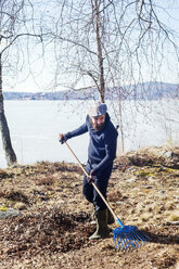 Mann beim Laubharken in Dalarna, Schweden - FOLF09669