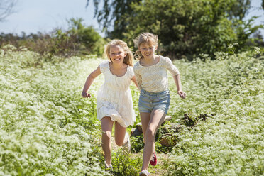Two teenage girls running through field in Blekinge, Sweden - FOLF09731