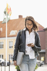 Junge Frau schaut auf ihr Handy in Solvesborg, Schweden - FOLF09744
