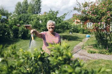 Ältere Frau bewässert Garten mit Schlauch - FOLF09766