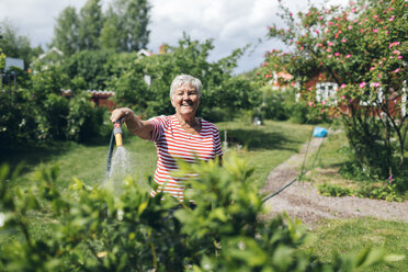 Senior woman watering garden with hose - FOLF09766