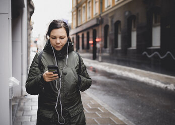 Frau hört auf der Straße in Stockholm, Schweden, ihr Smartphone ab - FOLF09783
