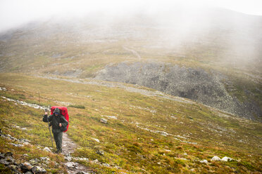 Mann beim Wandern auf einem Hügel im Pallas-Yllastunturi-Nationalpark in Lappland, Schweden - FOLF09863