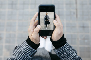 Mann hält Smartphone mit Foto von sich selbst, Nahaufnahme - JRFF02464