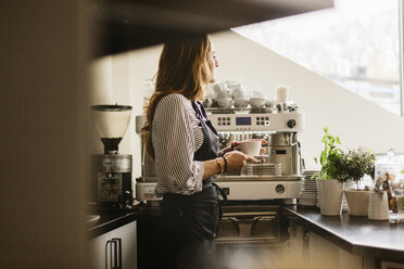 Barista hält Kaffee in der Küche eines Cafés - FOLF10029