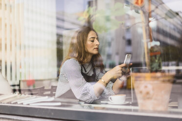 Barista benutzt Smartphone hinter dem Fenster des Cafés - FOLF10036