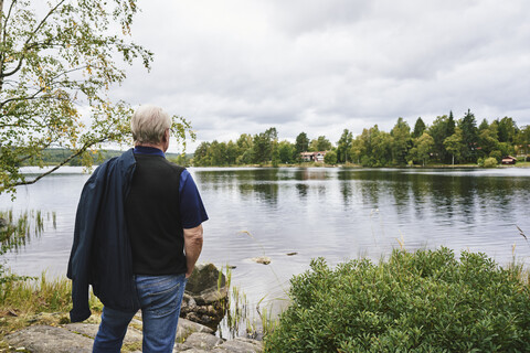 Älterer Mann steht am See in Falun, Schweden, lizenzfreies Stockfoto