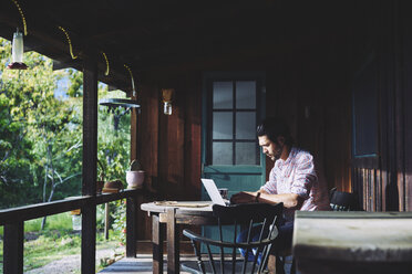 Mid adult man using laptop on verandah - FOLF10111