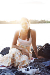 Junge Frau sitzt vor einem See in Dalarna, Schweden - FOLF10175