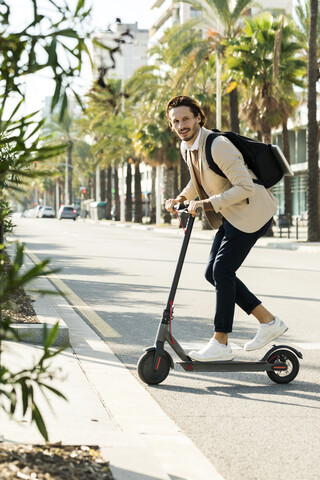 Man with backpack crossing the street on E-Scooter stock photo