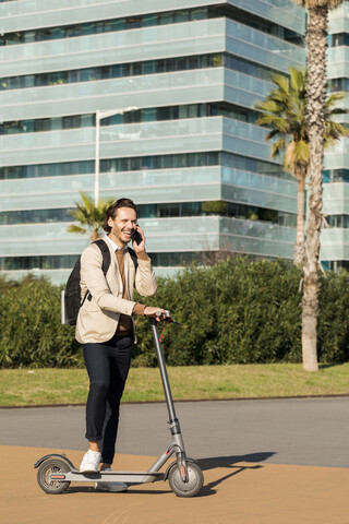 Laughing man on the phone with backpack and E-Scooter in the city stock photo