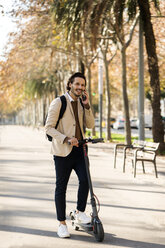 Man with backpack and E-scooter on the phone - VABF02085