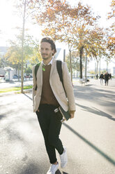 Portrait of man with backpack and skateboard in the city in autumn - VABF02092