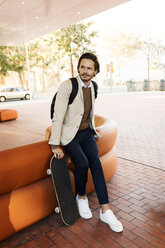 Portrait of man with backpack and skateboard in the city - VABF02095