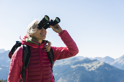 Österreich, Tirol, Frau schaut beim Wandern durch ein Fernglas, lizenzfreies Stockfoto