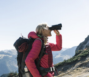 Österreich, Tirol, Frau schaut beim Wandern durch ein Fernglas - UUF16329