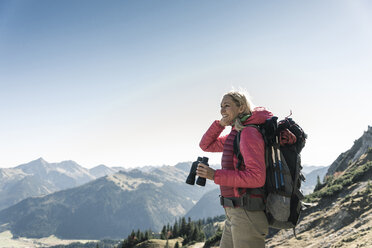 Österreich, Tirol, lächelnde Frau mit Fernglas auf einer Wandertour - UUF16345