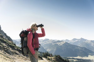 Österreich, Tirol, Frau schaut beim Wandern durch ein Fernglas - UUF16346