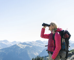 Österreich, Tirol, glückliche Frau schaut beim Wandern durch ein Fernglas - UUF16347