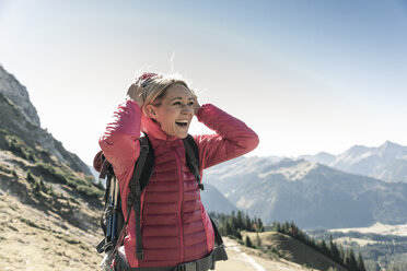 Austria, Tyrol, happy woman on a hiking trip in the mountains enjoying the view - UUF16351