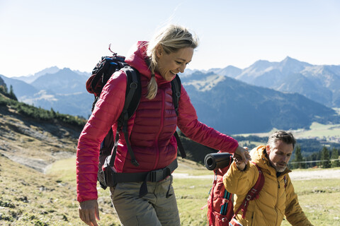 Österreich, Tirol, lächelndes Paar beim Wandern Hand in Hand in den Bergen, lizenzfreies Stockfoto