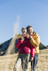Österreich, Tirol, glückliches Paar, das sich beim Wandern in den Bergen umarmt - UUF16397