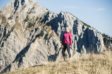 Österreich, Tirol, lächelnde Sportlerin auf Almwiese stehend - UUF16425