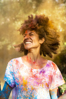 Frau schüttelt den Kopf, voll mit buntem Farbpulver, beim Feiern von Holi, dem Fest der Farben - ERRF00471