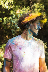 Man shaking his head, full of colorful powder paint, celebrating Holi, Festival of Colors - ERRF00472