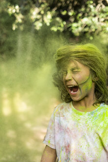 Junge schüttelt den Kopf, voll mit buntem Farbpulver, beim Feiern von Holi, dem Fest der Farben - ERRF00479