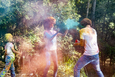 happy family celebrating Holi festival in the forest, throwing colorful powder paint - ERRF00499
