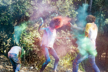 glückliche Familie, die das Holi-Fest im Wald feiert und mit buntem Farbpulver wirft - ERRF00500