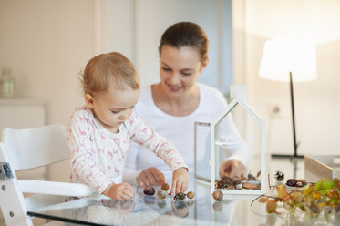 Mutter und kleine Tochter basteln ein herbstlich dekoratives Haus zu Hause - DIGF05574