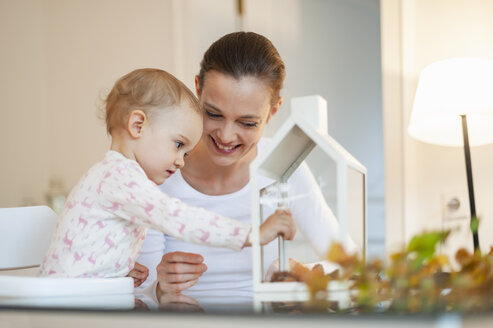 Mutter und kleine Tochter basteln ein herbstlich dekoratives Haus zu Hause - DIGF05575