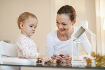 Glückliche Mutter und kleine Tochter basteln herbstliche Dekoration zu Hause - DIGF05577