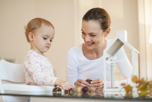 Happy mother and little daughter tinkering autumnal decorative house at home - DIGF05577