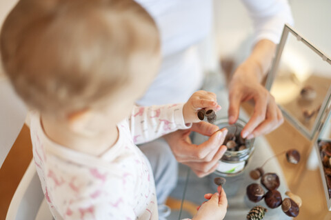 Nahaufnahme von Mutter und kleiner Tochter, die zu Hause an herbstlicher Dekoration basteln, lizenzfreies Stockfoto